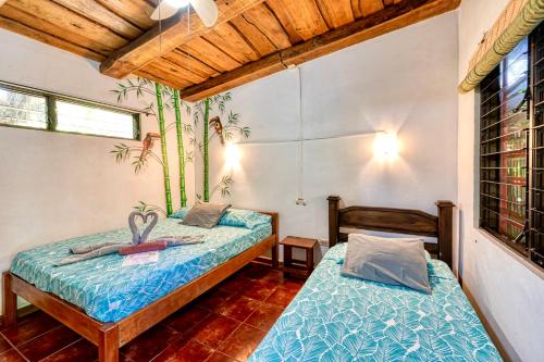 two twin beds in a room with wooden ceilings at Hotel Tropical Sands Dominical in Dominical