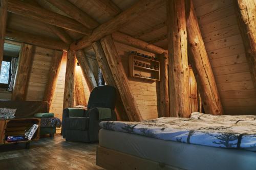 a bedroom with a bed and chairs in a log cabin at Domček v pieninach . in Majere
