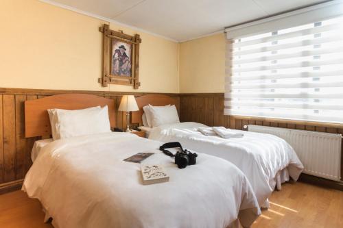 2 camas en una habitación de hotel con un libro en la cama en Hostal Hielo Sur en Punta Arenas