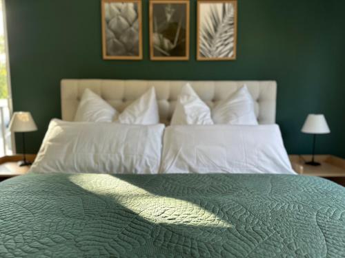 a green bedroom with a large bed with white pillows at Ferienwohnung-Parkplatz-Balkon-Küche-Aufzug-SmartTV-Waschtrockner in Erlangen