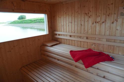 una sauna de madera con ventana y toalla roja en Hafen Perle - Übernachtungen auf dem Wasser- Romantik & Wellness auf dem Rhein - en Leverkusen