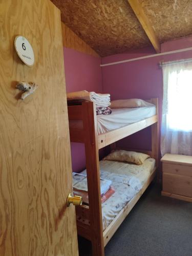 a bunk bed room with two bunk beds and a door at Alma Patagona Hostel in Puerto Tranquilo