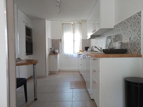 une cuisine avec des placards blancs, une table et une fenêtre dans l'établissement T3 Duplex tout confort, à Toulouse