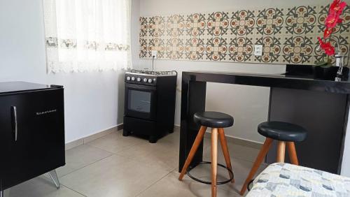 cocina con 2 taburetes y fogones en Hospedagem recanto do sábia flat 01, en Caparaó Velho