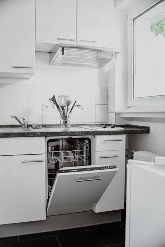 a kitchen with white cabinets and a dishwasher at Wiesbaden - Apartment im Nerotal in Wiesbaden