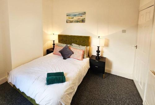 ein Schlafzimmer mit einem Bett mit einem grünen Kissen darauf in der Unterkunft Saint Helens, Warrington in Saint Helens