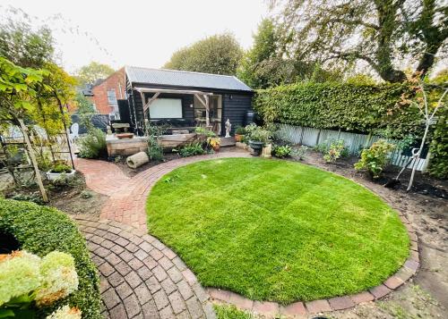 un jardín con césped circular frente a una casa en High spec studio cabin-Farnham centre en Farnham