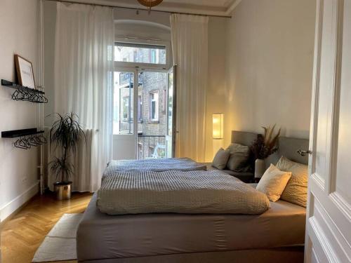 a bedroom with a large bed and a window at MyLivingOne I Friedrich I - Luxus-Apartment in Mannheim