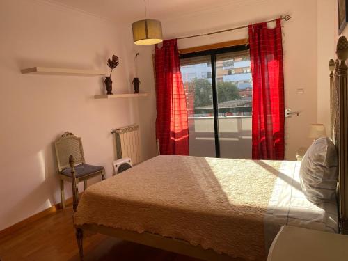 1 dormitorio con 1 cama y una ventana con cortinas rojas en Apartamento novo muito confortável com vista Rio en Algés