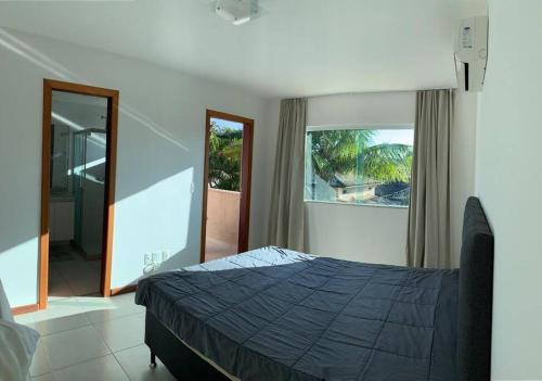 um quarto com uma cama e uma grande janela em Geriba casa do canto- 2 minutos da praia a pé em Búzios