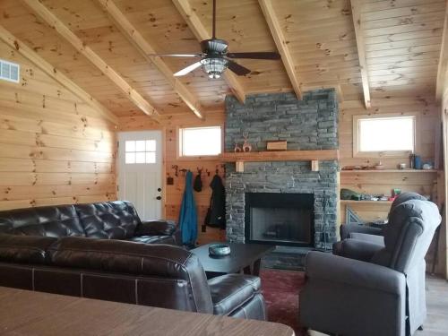 a living room with leather furniture and a stone fireplace at Timber Bend Retreat in Evart