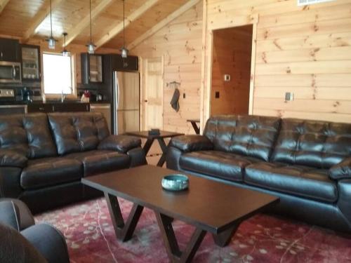 a living room with leather couches and a coffee table at Timber Bend Retreat in Evart