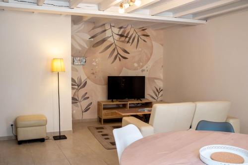 Una sala de estar con una mesa y un televisor. en Au Coeur du Village Bassillac Périgueux, en Bassillac