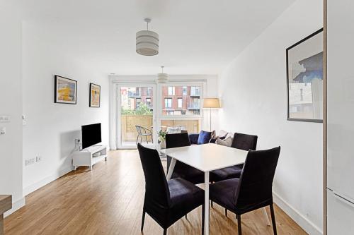 Beautiful Apartment in Surrey Quays في لندن: غرفة معيشة بيضاء مع طاولة وكراسي