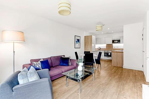 Beautiful Apartment in Surrey Quays في لندن: غرفة معيشة مع أريكة أرجوانية وطاولة
