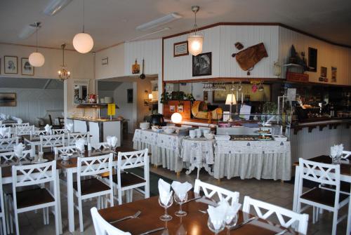 a restaurant with white tables and chairs and a kitchen at Haltinmaa Cottages in Kilpisjärvi