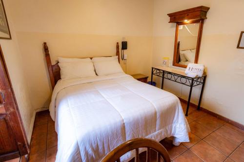 a bedroom with a white bed and a mirror at Hotel el Carmen in Morelia