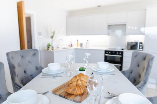 eine weiße Küche mit einem Tisch mit einem Teller Essen in der Unterkunft Luxury Cardiff City Centre Apartments in Cardiff
