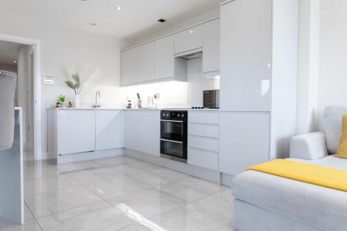 a white kitchen with white cabinets and a couch at Luxury Cardiff City Centre Apartments in Cardiff