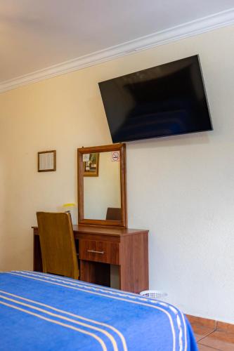 a bedroom with a bed and a mirror and a desk at Hotel el Carmen, Morelia in Morelia