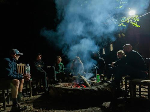 a group of people sitting around a fire at Guest house Hyrmet Demushi in Valbonë