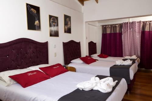 Habitación con 3 camas y toallas rojas y blancas. en Hotel Feimar en Cusco