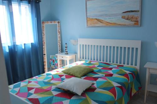 ein Schlafzimmer mit einem farbenfrohen Bett und einem Spiegel in der Unterkunft Recanto do Sol in Hortas