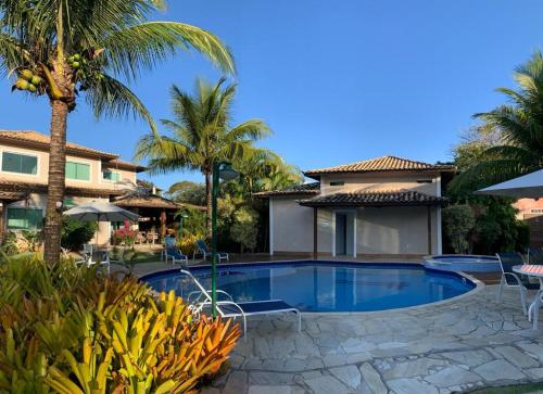 uma piscina com palmeiras e uma casa em Geriba casa do canto- 2 minutos da praia a pé em Búzios