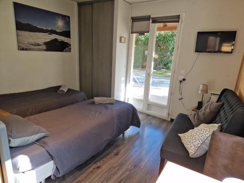 1 dormitorio con cama, sofá y TV en Studio La Cabane Centre Ville, en Le Bourg-dʼOisans