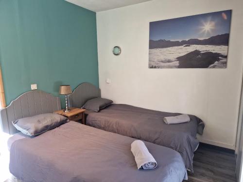 Habitación con 2 camas y una foto en la pared. en Studio La Cabane Centre Ville, en Le Bourg-dʼOisans