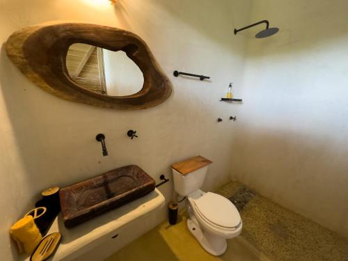 a bathroom with a toilet and a large wooden mirror at Casa Gitana in Chamuscadero