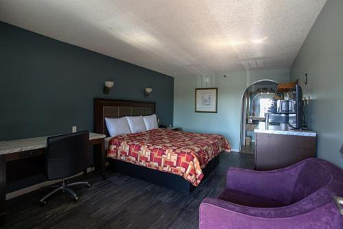 a hotel room with a bed and a desk and chair at Excel Inn & Suites in Fredericksburg