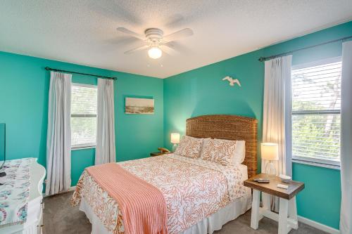 a blue bedroom with a bed and two windows at Coastal St Simons Retreat Near Gascoigne Bluff! in Saint Simon Mills