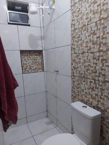 a bathroom with a white toilet and a shower at Casa de férias in Conceição da Barra
