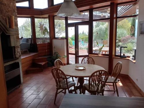 comedor con mesa, sillas y ventanas en Villa avec une piscine privée, en Quarante