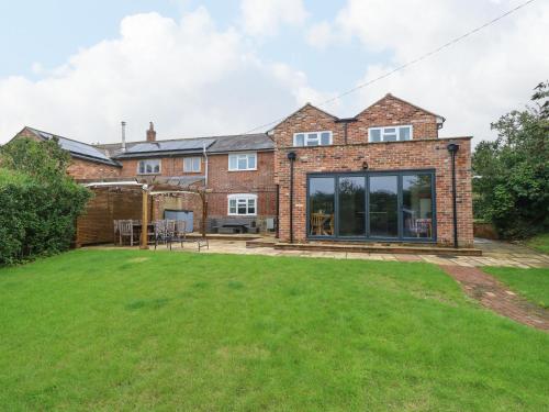 an extension to a brick house with a lawn at Frosthill Cottage in Newport