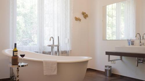 a white bathroom with a tub and a sink at Heger Tor Apartments in Osnabrück