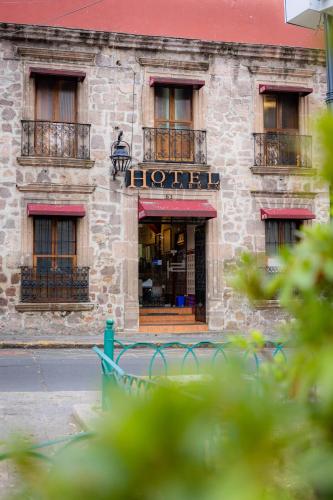a building with a bench in front of a store at Hotel el Carmen, Morelia in Morelia