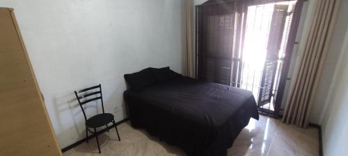 een slaapkamer met een bed, een stoel en een raam bij Quarto em casa a 1.4km da UFSM in Santa Maria