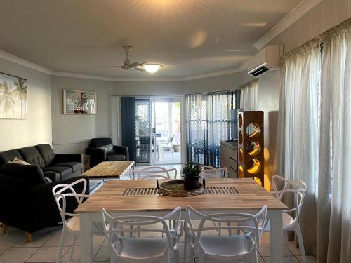 Villa Venezia Apt 3 - Spacious Hervey Bay beachfront apartment في خليج هيرفي: غرفة معيشة مع طاولة وكراسي وأريكة