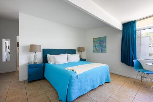 een slaapkamer met een blauw bed en een blauwe stoel bij Monkey Tree Hotel by AvantStay Stylish Hotel in Palm Springs w Pool in Palm Springs