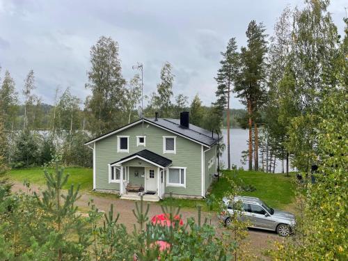 a green house with a car parked in front of it at Tarula Holiday Home in Melkoniemi