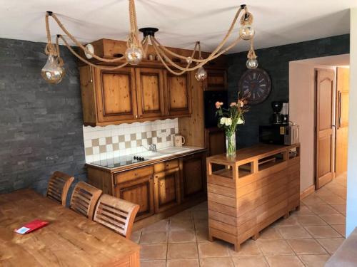 une cuisine avec des placards en bois et un vase de fleurs sur une table dans l'établissement Superbe appart cosy, piscine terrasse, ascenseur., à Cohennoz