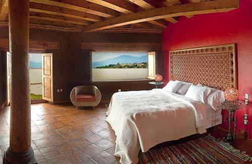 a bedroom with a large bed with a red wall at Hacienda Ucazanaztacua in Pátzcuaro