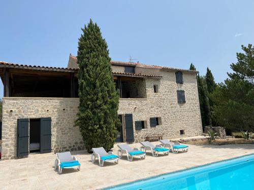 eine Villa mit einem Pool und einem Haufen Liegestühle in der Unterkunft Luxurious family house with pool in Ardèche. in Les Vans
