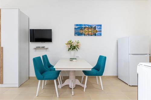 cocina con mesa blanca y sillas azules en Apartments Lustica en Tivat