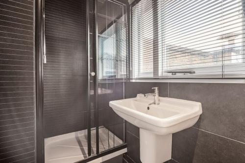 a bathroom with a sink and a glass shower at Spacious Home on Chapel Market in London