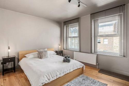 a bedroom with a large bed and two windows at Spacious Home on Chapel Market in London