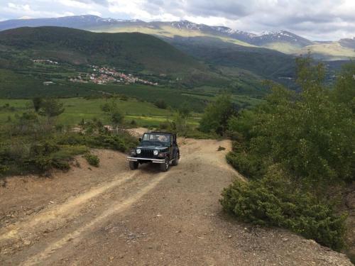 a jeep driving down a dirt road in the mountains at La Ruota Hotel Sharr in Dragash