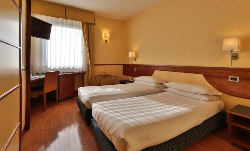 a hotel room with two beds and a desk at Best Western Hotel I Colli in Macerata
